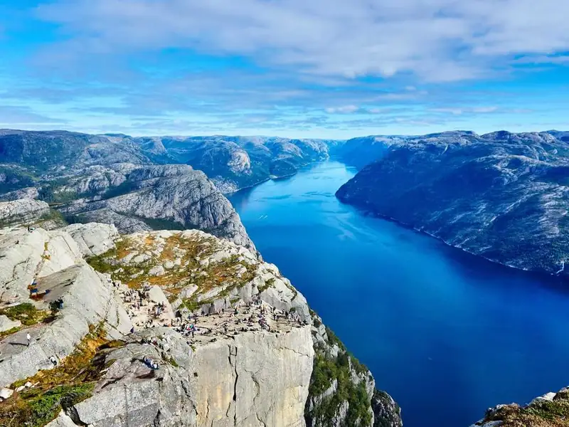 Deep blue fjord between grey granite cliffs, seen from a high rocky ledge